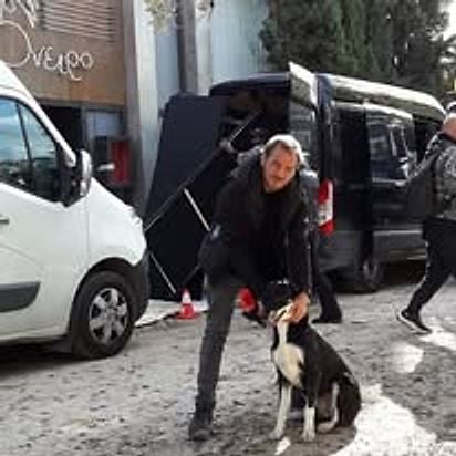 Εκπαιδευτής με σκύλο σε εξωτερικό γύρισμα, δίπλα στα βαν της παραγωγής